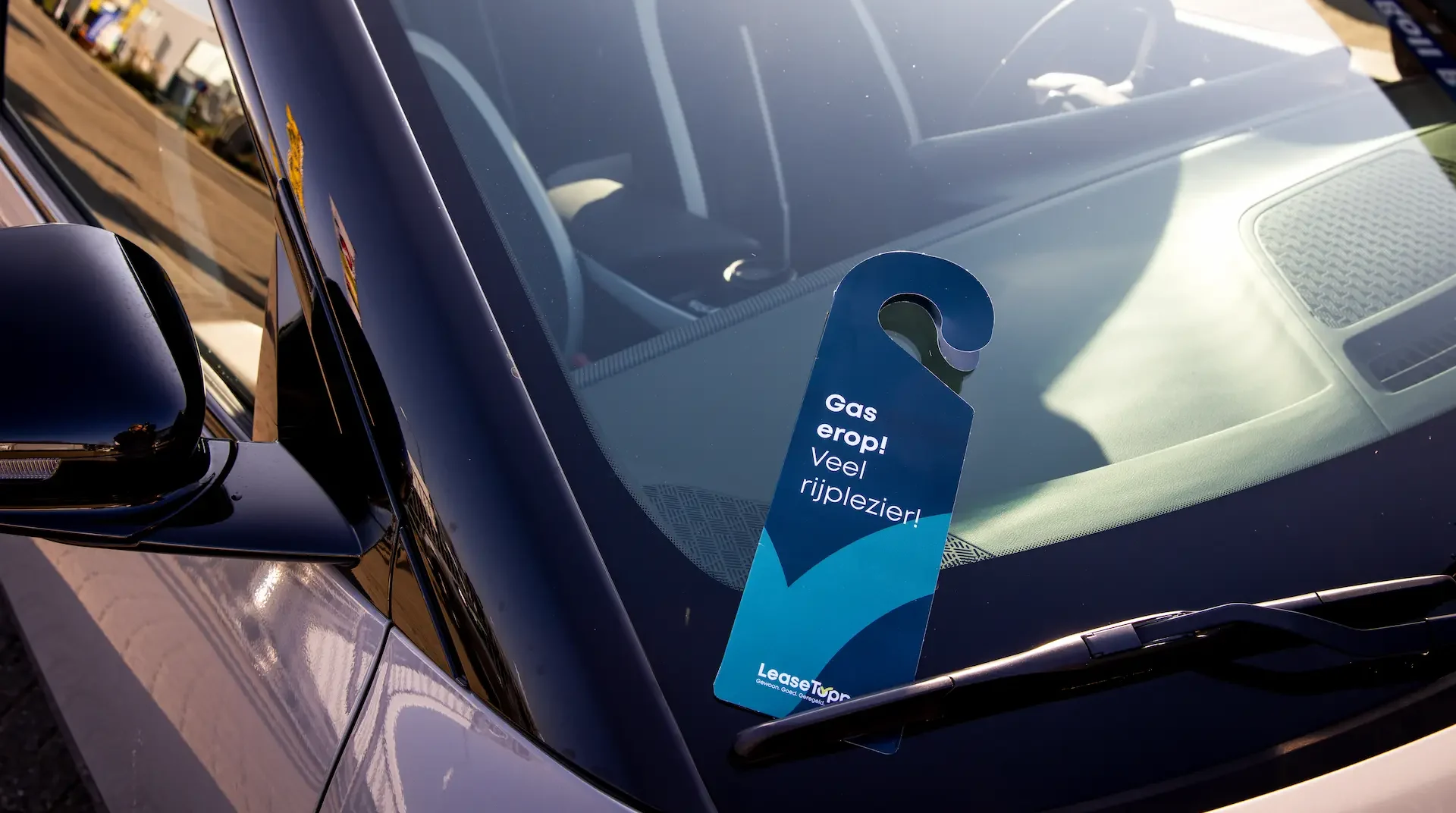 deurhanger van Leasetoppers tussen de ruitenwisser van de auto. Fotografie voor Leasetoppers